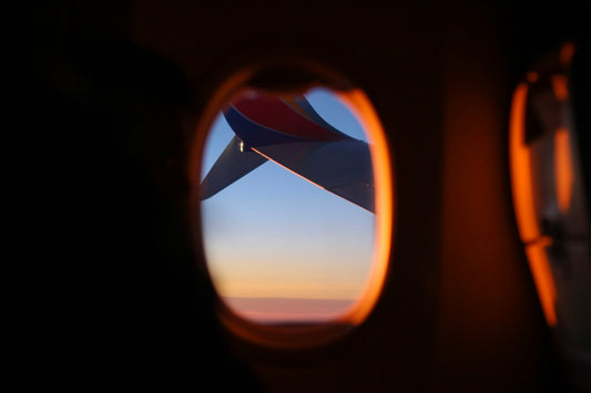 Sunrise light through an airplane window above the clouds on an early morning flight
