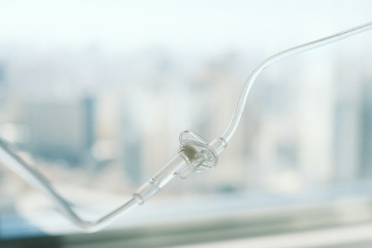 Close-up of an IV drip line in soft focus, illustrating the slow, steady delivery of an NAD+ infusion